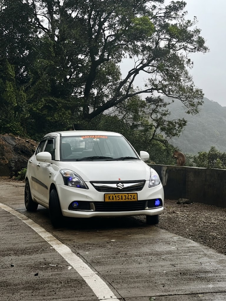 White Maruti Swift Dzire sedan of Navyashree Travels parked on a misty Western Ghats road